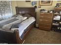 Bedroom with a wooden bedframe, neutral carpet, and decorative pillows, dresser, shelving and accessories at 16696 W Culver St, Goodyear, AZ 85338