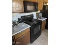 Picture of a kitchen featuring a black stove, microwave, wooden cabinets, and light countertops at 16696 W Culver St, Goodyear, AZ 85338