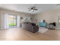 Inviting living room with light wood floors, a ceiling fan, and sliding glass doors to the backyard at 17560 W Young St, Surprise, AZ 85388