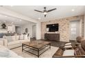 Open-concept living room featuring a brick accent wall and dark wood flooring at 19595 W San Miguel Ave, Litchfield Park, AZ 85340