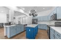 Bright kitchen features blue cabinetry, a central island, stainless steel appliances, and modern lighting at 757 W Carob Way, Chandler, AZ 85248