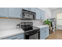 Close-up of kitchen showcasing black appliances, light countertops, and blue cabinets with modern hardware at 757 W Carob Way, Chandler, AZ 85248