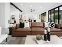 Modern living room with vaulted ceiling, black beams, leather sofa, and expansive sliding glass doors at 7774 E San Fernando Dr, Scottsdale, AZ 85255