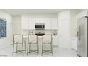 Modern kitchen features white cabinetry, stainless steel appliances, and a breakfast bar with seating at 9534 W Catalina Dr, Phoenix, AZ 85037