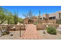 Brick-lined walkway leading to a neutral home with desert landscaping and a gated courtyard at 2304 Fox Tail Trl, Carefree, AZ 85377