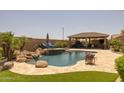 Backyard pool featuring rock waterfall, tanning deck and outdoor kitchen area at 3119 E Bellflower Dr, Gilbert, AZ 85298