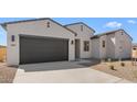 Stunning view of a one-story home with a dark garage door and desert landscaping at 37695 W Santa Maria St, Maricopa, AZ 85138
