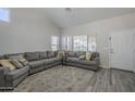 Bright living room with a high ceiling, neutral paint, hardwood flooring, and a comfortable gray sofa at 7930 W Colter St, Glendale, AZ 85303