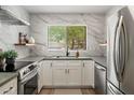 Bright kitchen features white cabinets, modern stainless steel appliances, and stylish countertops with marble backsplash at 810 E Potter Dr, Phoenix, AZ 85024