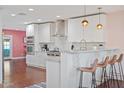 Modern kitchen with stainless steel appliances, white cabinets, marble countertops, and a breakfast bar with seating for three at 8102 E Cambridge Ave, Scottsdale, AZ 85257