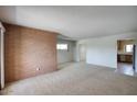 Open-concept living room with brick accent wall and view into adjacent kitchen at 12220 N 22Nd Pl, Phoenix, AZ 85022