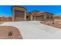 Spacious concrete driveway leading to a three car garage and charming stone accented single story home at 17308 W Royal Palm Rd, Waddell, AZ 85355
