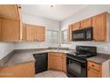 Functional kitchen with wood cabinets, black appliances, a dual basin sink, and tile flooring at 2311 E Hartford Ave # 29, Phoenix, AZ 85022