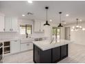 Bright kitchen showcasing white cabinetry, a black island with marble countertop, and an open layout at 313 N 101St Way, Mesa, AZ 85207