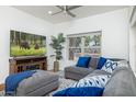 Bright living room with hardwood floors, gray sectional sofa, ceiling fan, and a large window at 3204 N Jay St, Chandler, AZ 85225