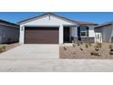 Inviting single-story home with a brown two-car garage, stone detailing and xeriscaped front yard at 3510 N Camden Dr, Florence, AZ 85132