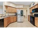 Well-equipped kitchen with stainless steel refrigerator, light-wood cabinets and black appliances at 4427 W Powell Dr, New River, AZ 85087