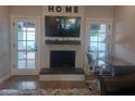 Cozy living room with a charming fireplace, hardwood floors, and double french doors leading to the backyard at 8879 E Friess Dr, Scottsdale, AZ 85260