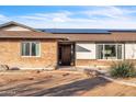 Front exterior showcases a brick and stucco finish, a rustic wooden door, and modern solar panels on the roof at 1044 E Irvine Rd, Phoenix, AZ 85086