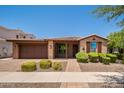 Charming single-story brick home with a tiled roof, manicured landscaping, and a two-car garage at 10618 E Kinetic Dr, Mesa, AZ 85212