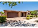 Charming single-story brick home with manicured landscaping, tiled roof, and a two-car garage at 10618 E Kinetic Dr, Mesa, AZ 85212