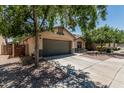 View of the home with mature trees, 2 car garage, and a side yard with privacy fence at 12325 W Berridge Ln, Litchfield Park, AZ 85340