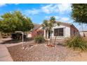 A beautiful white single-story house with desert landscaping, rock accents, and mature trees at 1432 E Penny Ln, San Tan Valley, AZ 85140