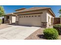 A beige house features a two-car garage with stone pillars and a wide driveway, perfect for multiple vehicles at 15429 W Ventura St, Surprise, AZ 85379
