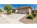 A beige house has a garage, a driveway, and green bushes out front, nestled in a sunny neighborhood at 15429 W Ventura St, Surprise, AZ 85379