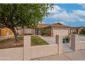 Inviting single-story home features a well-manicured lawn, mature trees, and an expansive driveway with a two-car garage at 1814 N 89Th Ave, Phoenix, AZ 85037