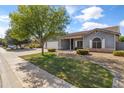 Inviting single-story home featuring a landscaped yard, covered porch, and gray siding with stone accents at 20464 E Bronco Dr, Queen Creek, AZ 85142