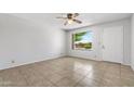 Bright bedroom with neutral tile flooring, a ceiling fan, and a window offering a pleasant view of the outdoors at 2064 S Farnsworth Dr # 43, Mesa, AZ 85209