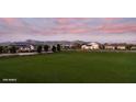 Scenic view of neighborhood homes nestled against a mountain backdrop and expansive green space at sunset at 21963 E Sunset Dr, Queen Creek, AZ 85142