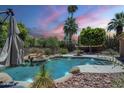 Backyard view of a gorgeous pool area with stone accents, lush trees, and a covered patio for relaxing at 2340 W Myrtle Dr, Chandler, AZ 85248