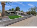 Single story home featuring an updated desert landscape with low walls, artificial grass, and a mature shade tree at 3825 E Captain Dreyfus Ave, Phoenix, AZ 85032