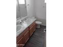 Bright bathroom with double sinks, wood cabinets, new fixtures, and modern vinyl floors at 7284 E Gamebird Way, San Tan Valley, AZ 85143