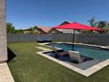 Backyard oasis featuring a pool with baja step, lounge chairs and artificial grass at 10430 W Los Gatos Dr, Peoria, AZ 85383