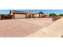 View of the front yard with desert landscaping and a long driveway leading to the two-car garage at 10820 N 45Th Dr, Glendale, AZ 85304
