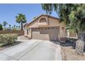 Tan single-story home featuring a two-car garage and low maintenance desert landscaping at 1616 N 125Th Ln, Avondale, AZ 85392