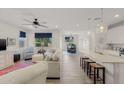 Bright, open-concept living room with tile floors, ceiling fan, a colorful rug and kitchen with island in the background at 20904 E Swan Dr, Queen Creek, AZ 85142