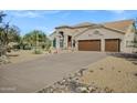 Home's extra-long driveway leads to a three-car garage surrounded by desert landscaping at 26475 N Wrangler Rd, Scottsdale, AZ 85255