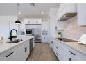 Bright kitchen with white cabinets, marble backsplash, stainless appliances and island seating at 29587 N 156Th St, Scottsdale, AZ 85262