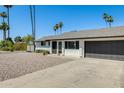 Beautiful one story white brick house featuring a dark garage door, gravel yard and mature landscaping at 9214 N 54Th Ave, Glendale, AZ 85302
