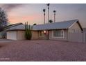 Well-maintained single-story house featuring desert landscaping and palm trees at sunset at 1055 E Ingram St, Mesa, AZ 85203