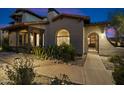 Inviting Southwestern-style home with arched entry gate, lush desert landscaping, and covered porch at 17903 N 93Rd Way, Scottsdale, AZ 85255