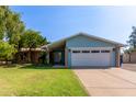 Charming single-story home with a well-maintained lawn, mature trees, and a two car garage at 2161 E Harmony Cir, Mesa, AZ 85204