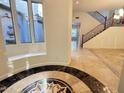 Spacious foyer showcasing elegant tile flooring, staircase, and tranquil courtyard view at 22903 N 39Th Ter, Phoenix, AZ 85050