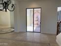 Bright living area with tile flooring, decorative inlays, sliding glass doors, and a view of a tiered fountain at 22903 N 39Th Ter, Phoenix, AZ 85050
