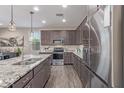 Modern kitchen featuring stainless steel appliances, granite countertops, and wood-look tile flooring at 22920 E Indiana Ave, Queen Creek, AZ 85142