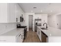 Open kitchen features white cabinets, stainless steel appliances, large island and pantry at 5023 W Hardtack Trl, Laveen, AZ 85339